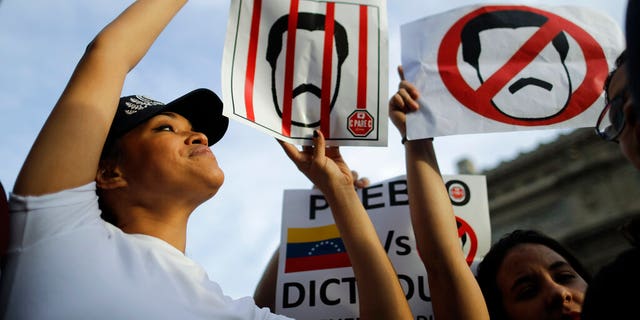 Venezuelan anti-government protesters hold signs against Venezuelan President Nicolas Maduro during a demonstration in Buenos Aires, Argentina, Wednesday, Jan. 23, 2019. Hundreds of people, mostly Venezuelan migrants, held a rally against Maduro and in favor of Juan Guaido, head of Venezuela's opposition-run congress who today proclaimed himself president of the South American nation. 