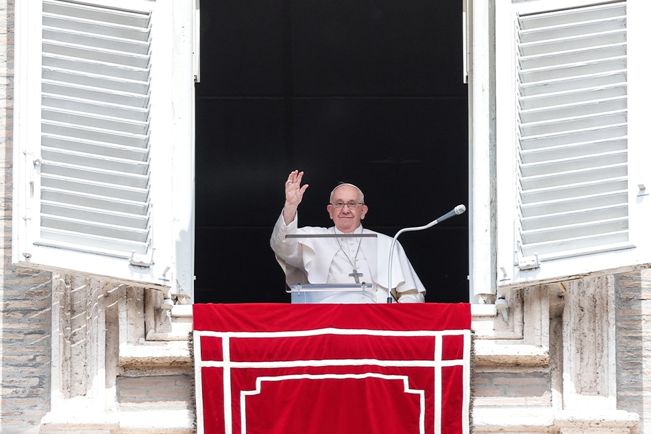Pope Francis waves from his office window overlooking Saint Peter
