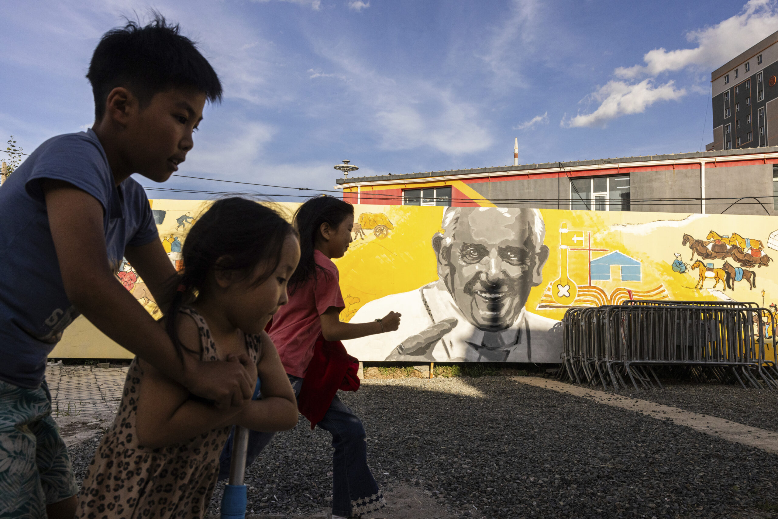 Children run past a mural featuring Pope Francis outside Saints Peter and Paul Catholic Cathedral in Ulaanbaatar, Mongolia, Aug. 31, 2023. (Louise Delmotte—AP)